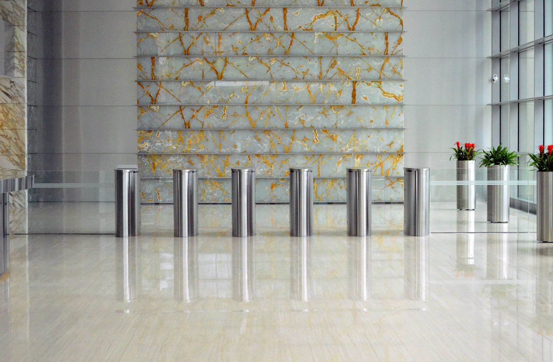 A sleek corporate lobby featuring marble walls, metal dividers, and glass windows.
