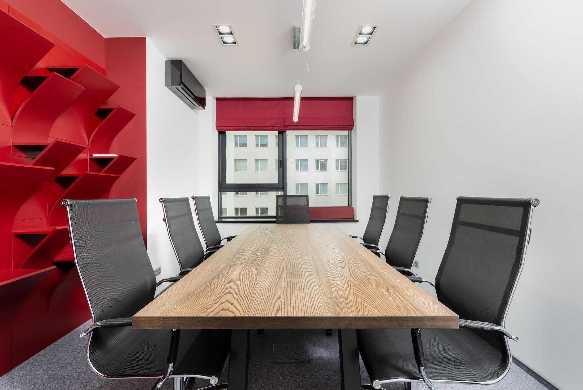 Interior of modern conference room with wooden table and chairs next to shelves near window